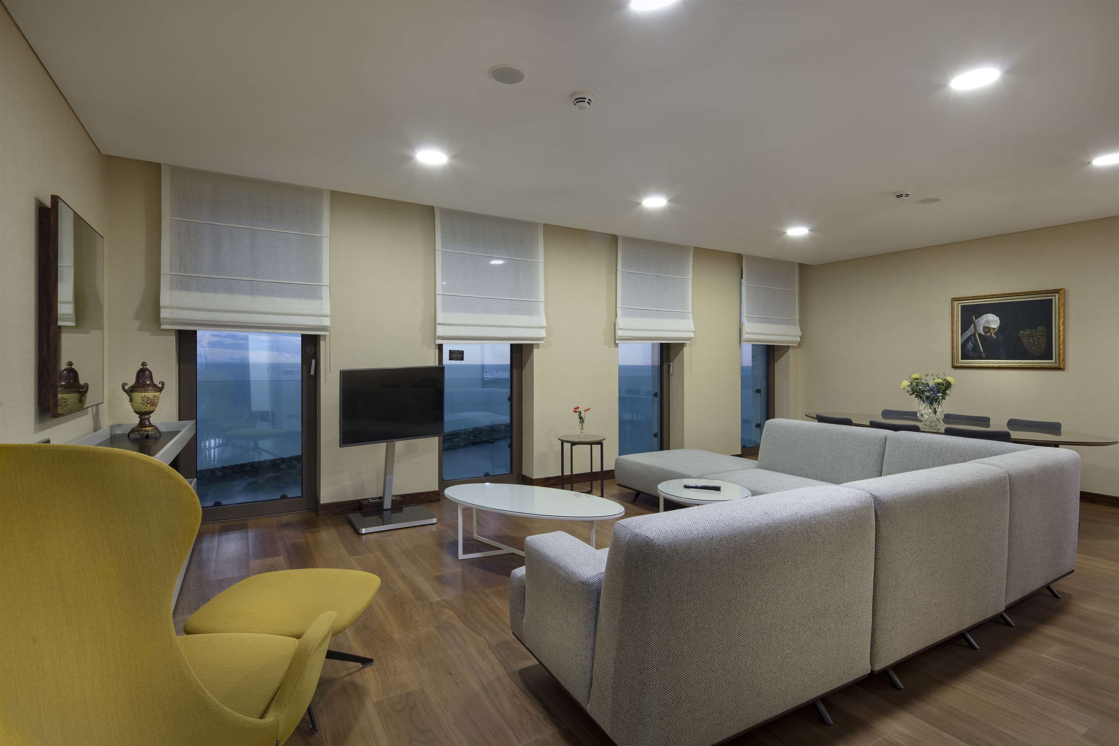 Una sala de estar moderna con un sofá, un sillón amarillo y un televisor de pantalla plana.