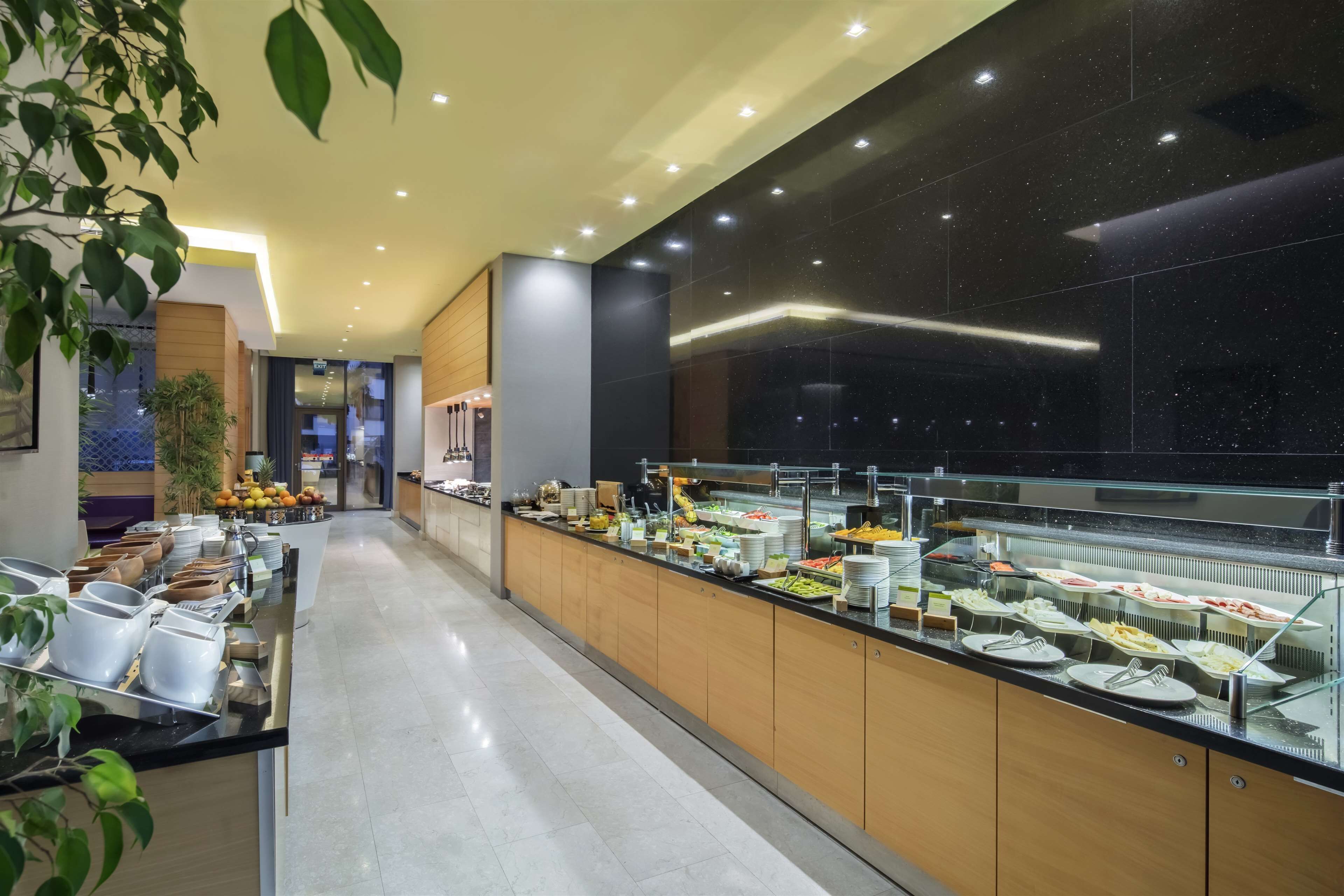 A modern hotel lobby with a long buffet counter, glass display cases, and a clean, well-lit interior.