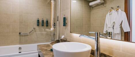 Un baño moderno con una bañera independiente, un espejo grande y un tocador con lavamanos.