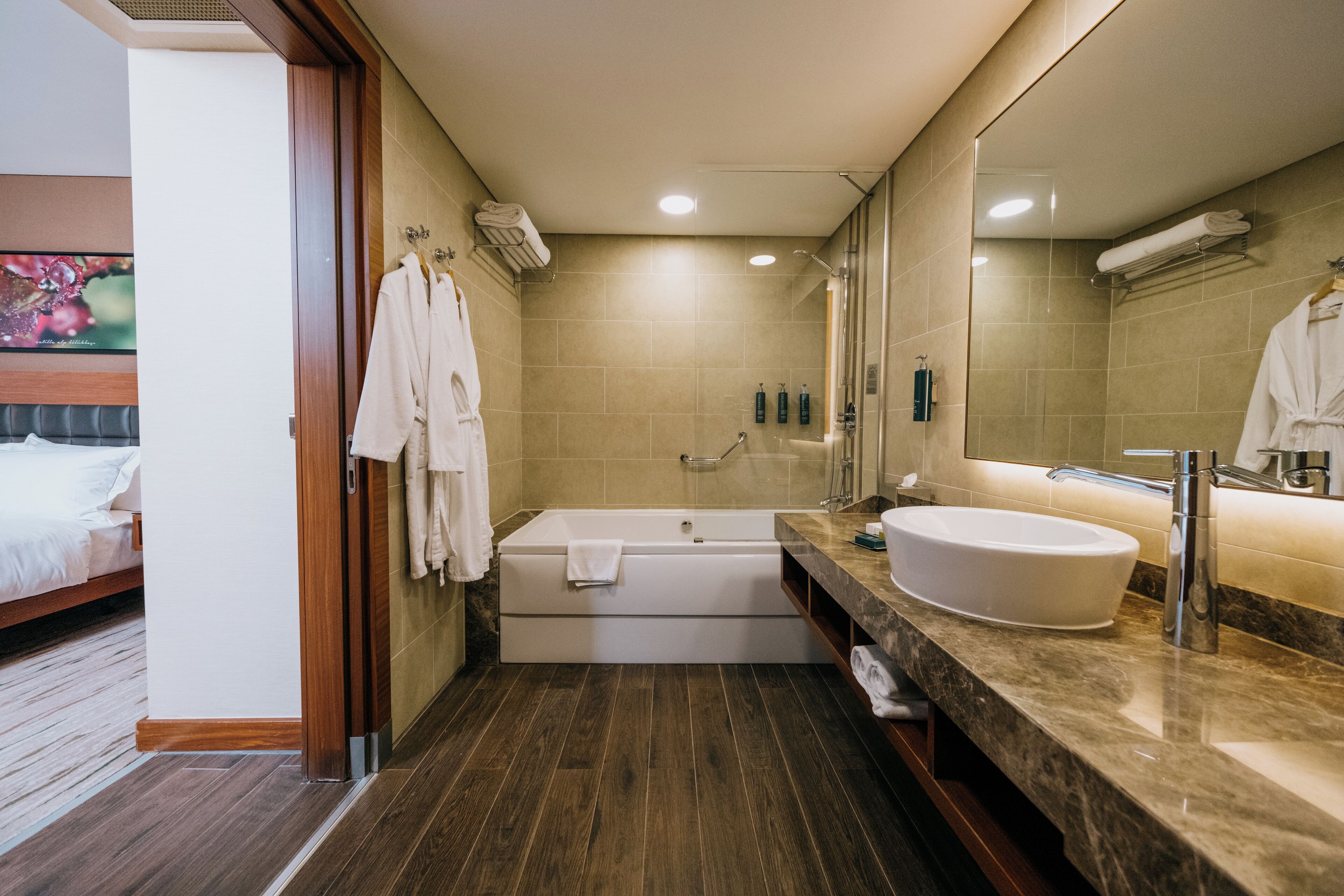 A modern bathroom with a bathtub, a large mirror, a sink, and a shower.