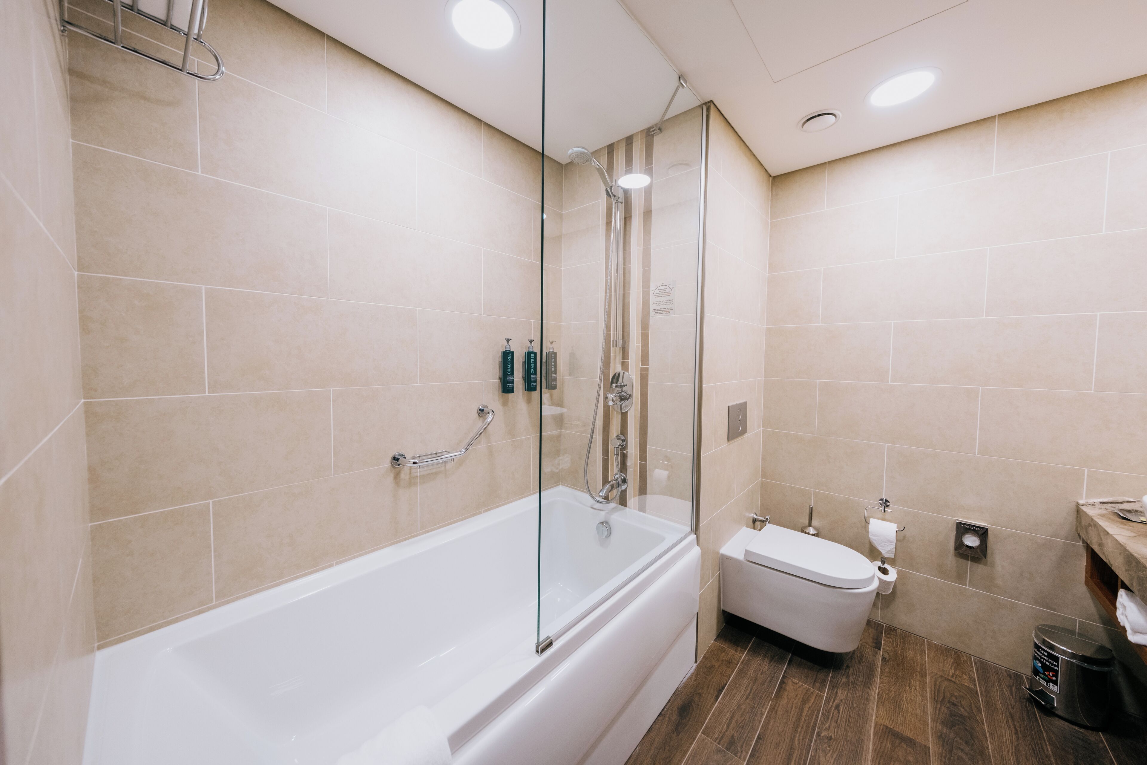 A modern bathroom with a glass-enclosed shower, a white bathtub, and a toilet.