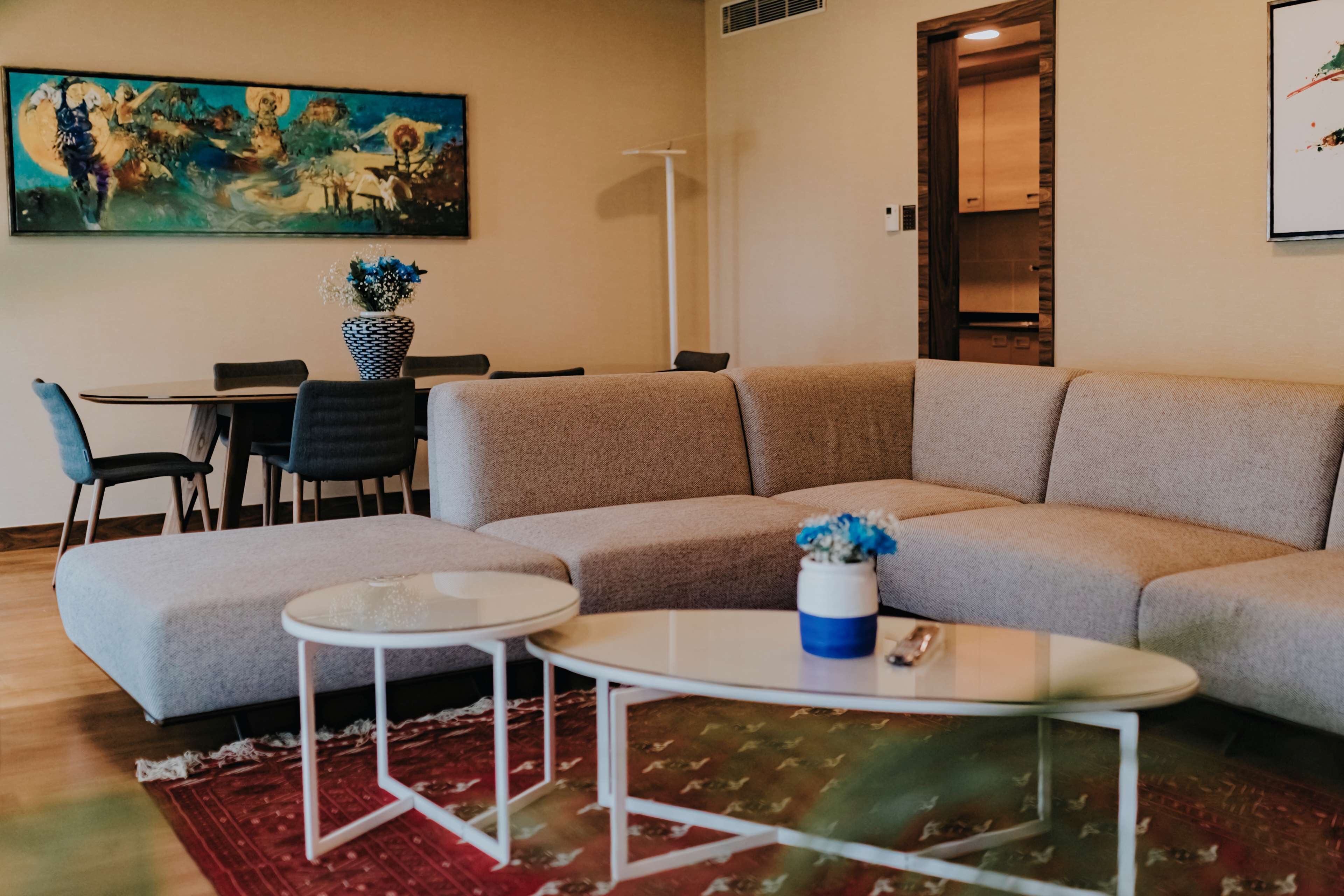 Una sala moderna con un sofá modular, una mesa de comedor con sillas y una mesa de centro.