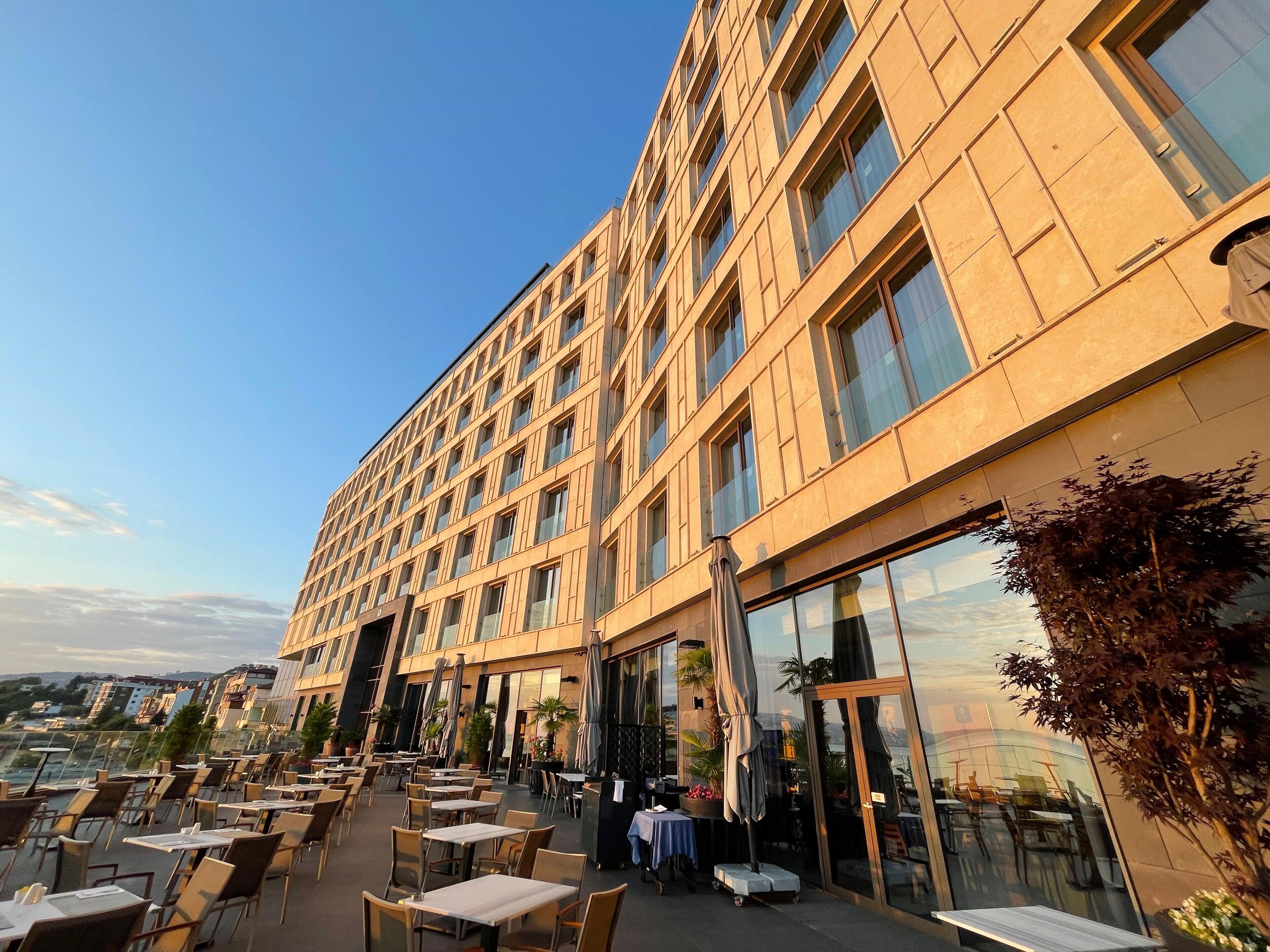 A hotel with outdoor seating and a view of the city.