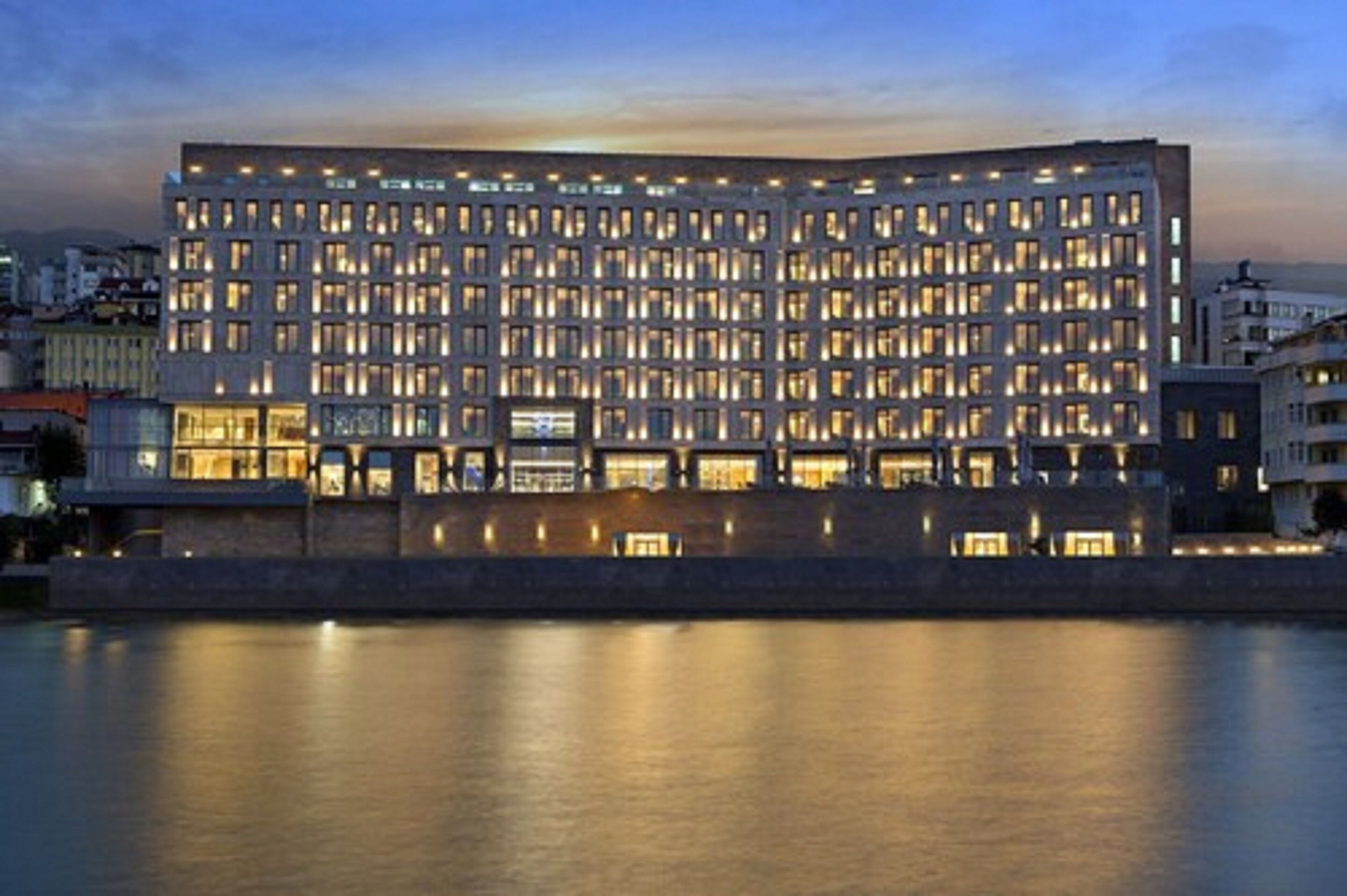 A modern hotel with a rectangular facade, multiple floors, and illuminated windows.