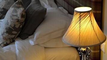 A hotel room with a bed, two bedside lamps, and a wooden nightstand.