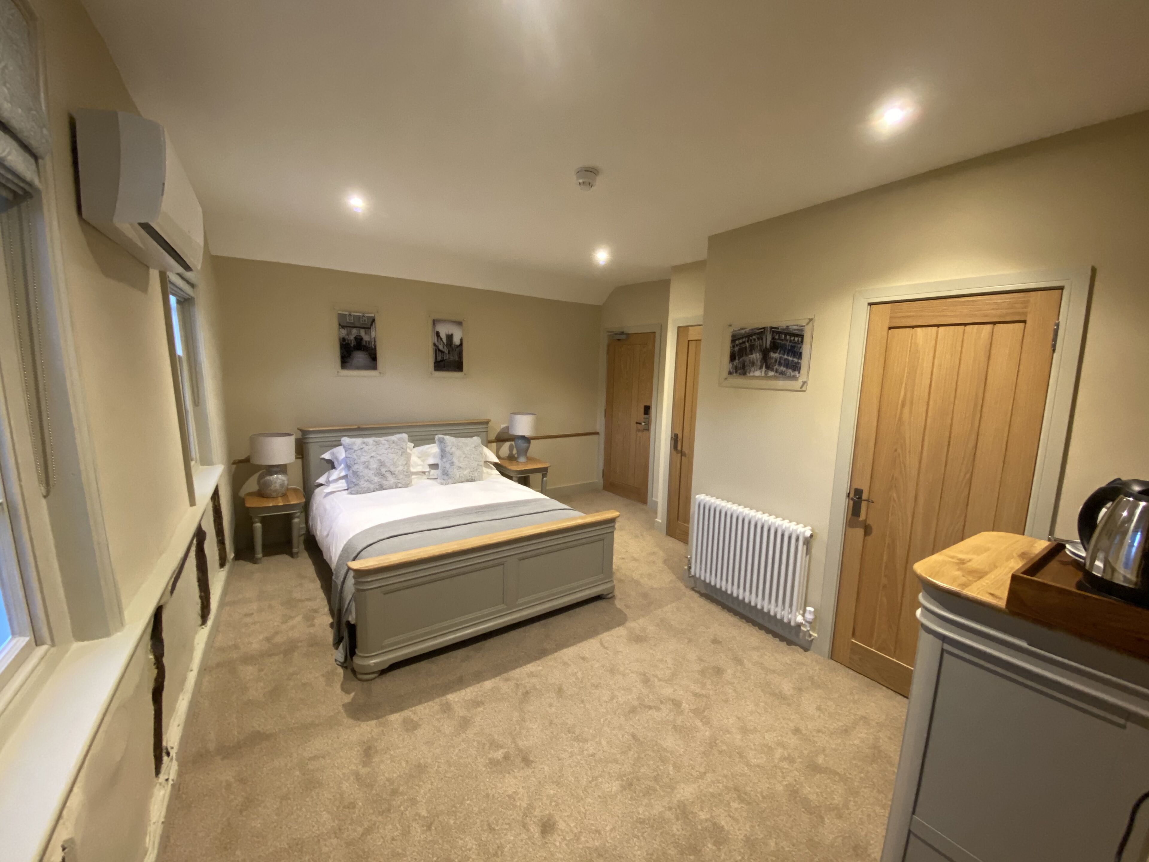 Une chambre à coucher avec un grand lit, des tables de chevet, un radiateur et une porte en bois.