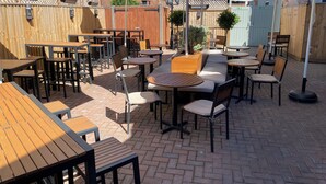 An outdoor patio with tables and chairs, umbrellas, and a wooden fence. - The Peppermill (Devizes)