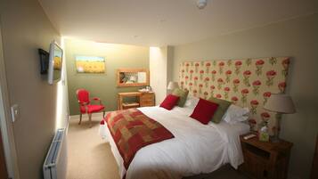 A bedroom with a bed, bedside tables, a chair, a desk, and a radiator.