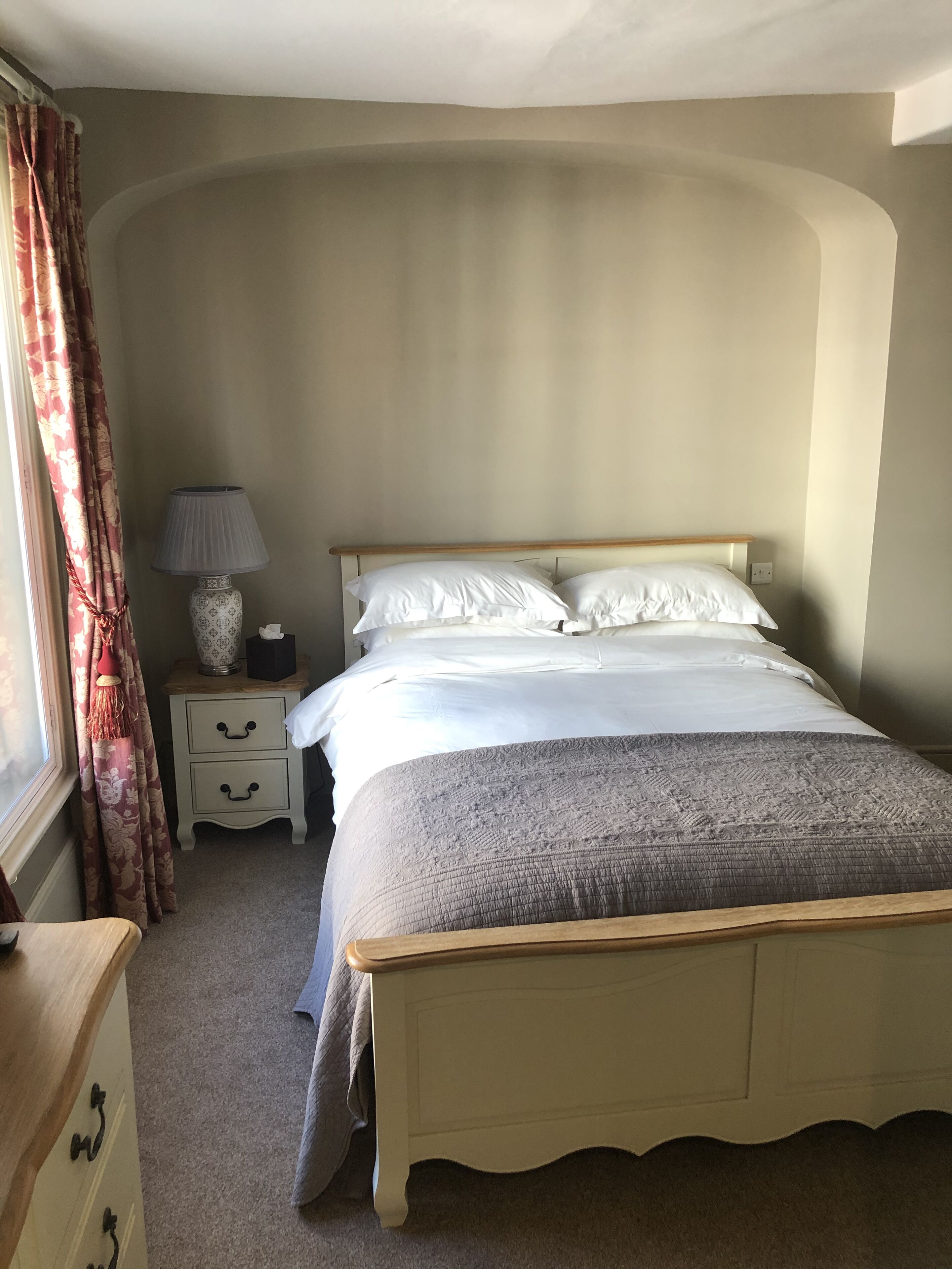 Un dormitorio con cama, mesita de noche, lámpara y cómoda.