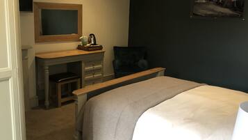 Un dormitorio con cama, escritorio, silla, televisor y un cuadro en la pared.
