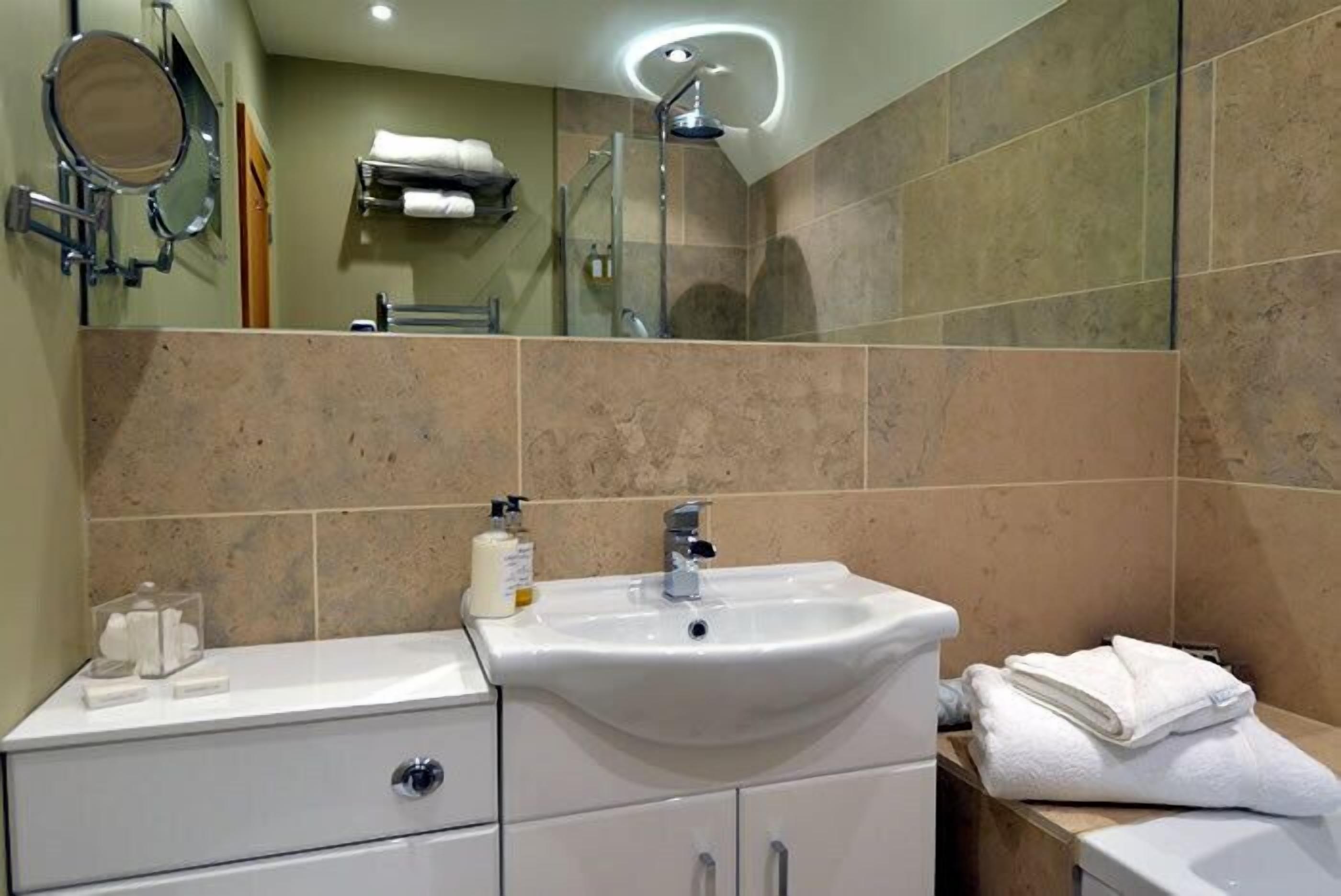 A modern bathroom with a sink, mirror, and shower.