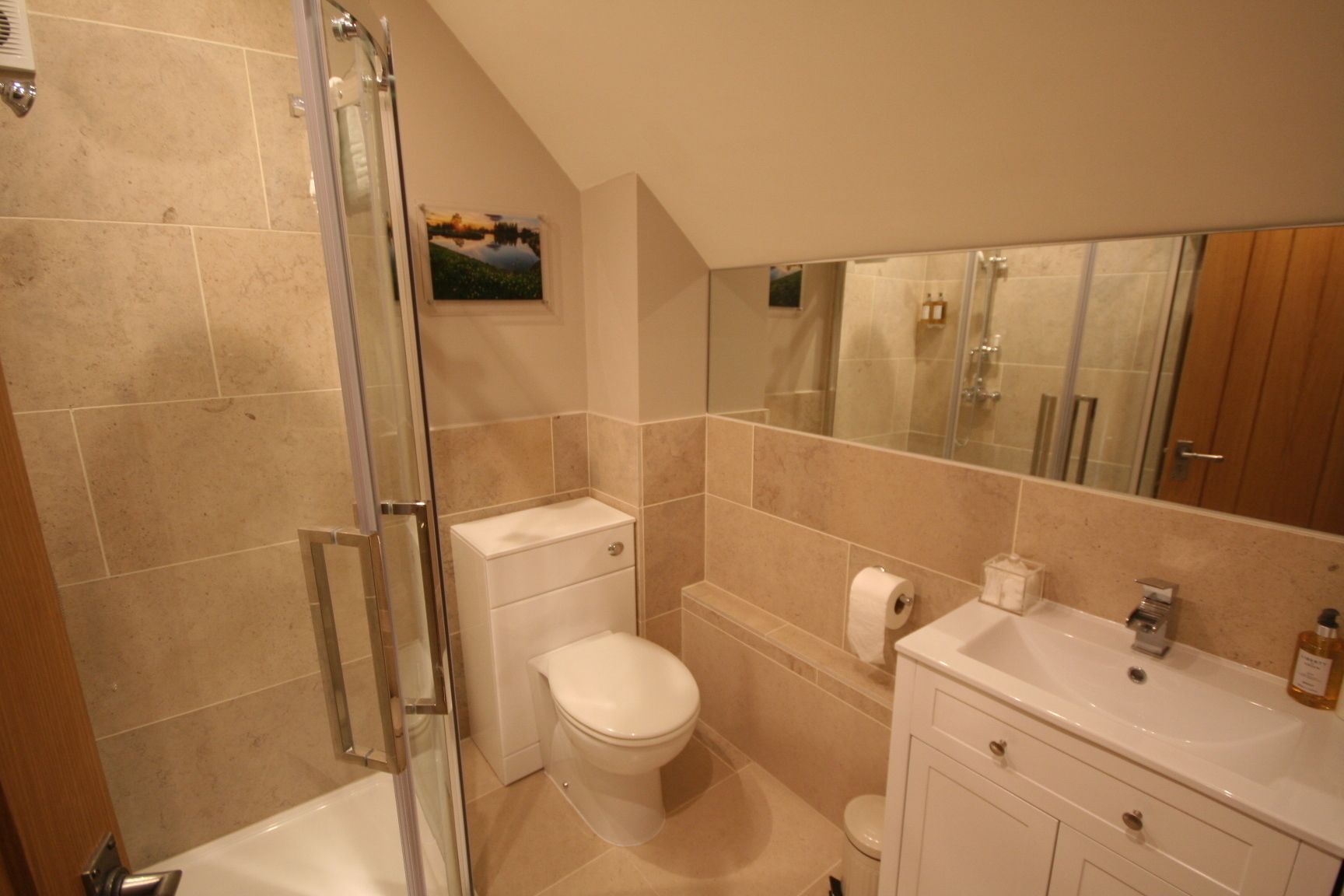 A bathroom with a shower, toilet, sink, and a mirror.