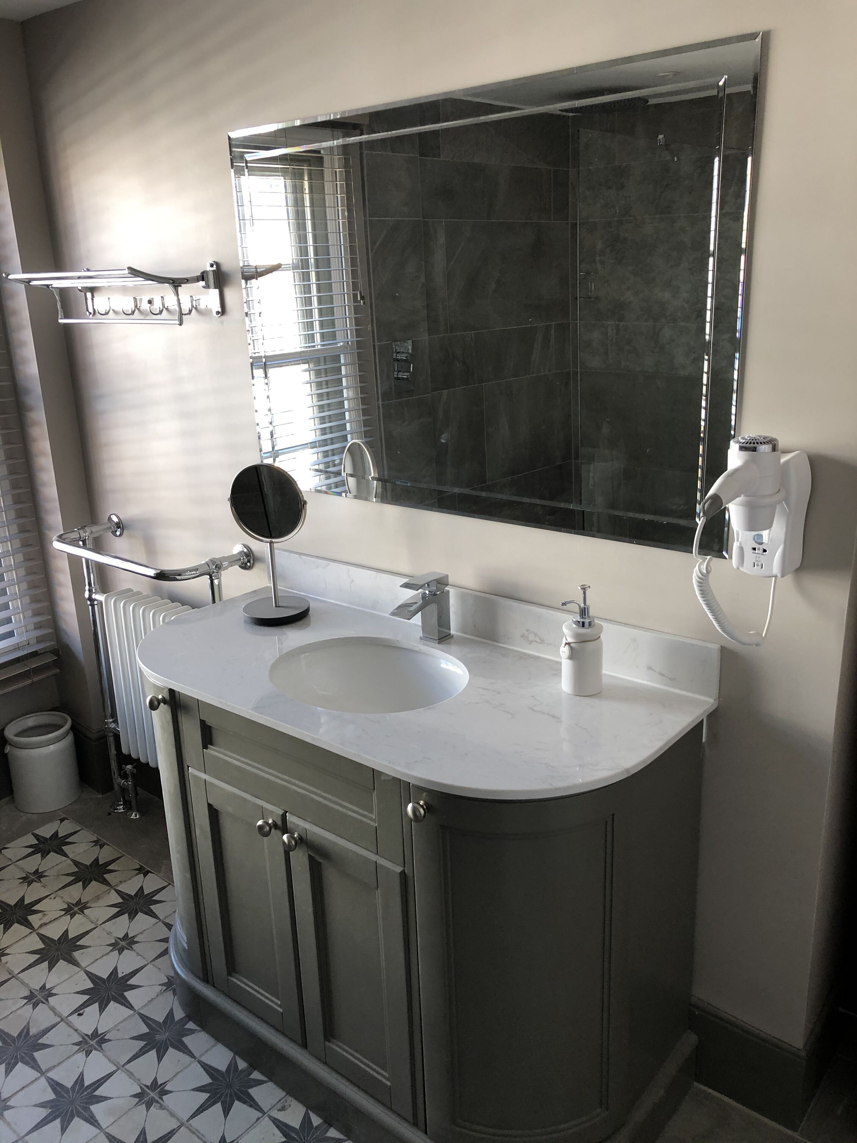Casa de banho com lavatório duplo, espelho grande, porta-toalhas e radiador.