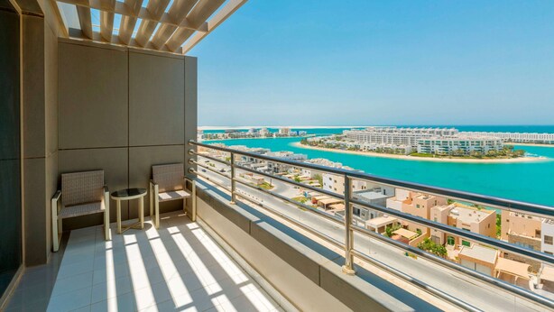 Un balcó amb vistes a una ciutat costanera, incloent un port esportiu i edificis residencials.
