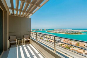 Un balcón con vista a un paisaje urbano costero, que incluye un puerto deportivo y edificios residenciales.