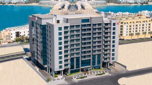 Un hotel modern amb un atrium central, diverses plantes i vista al mar.