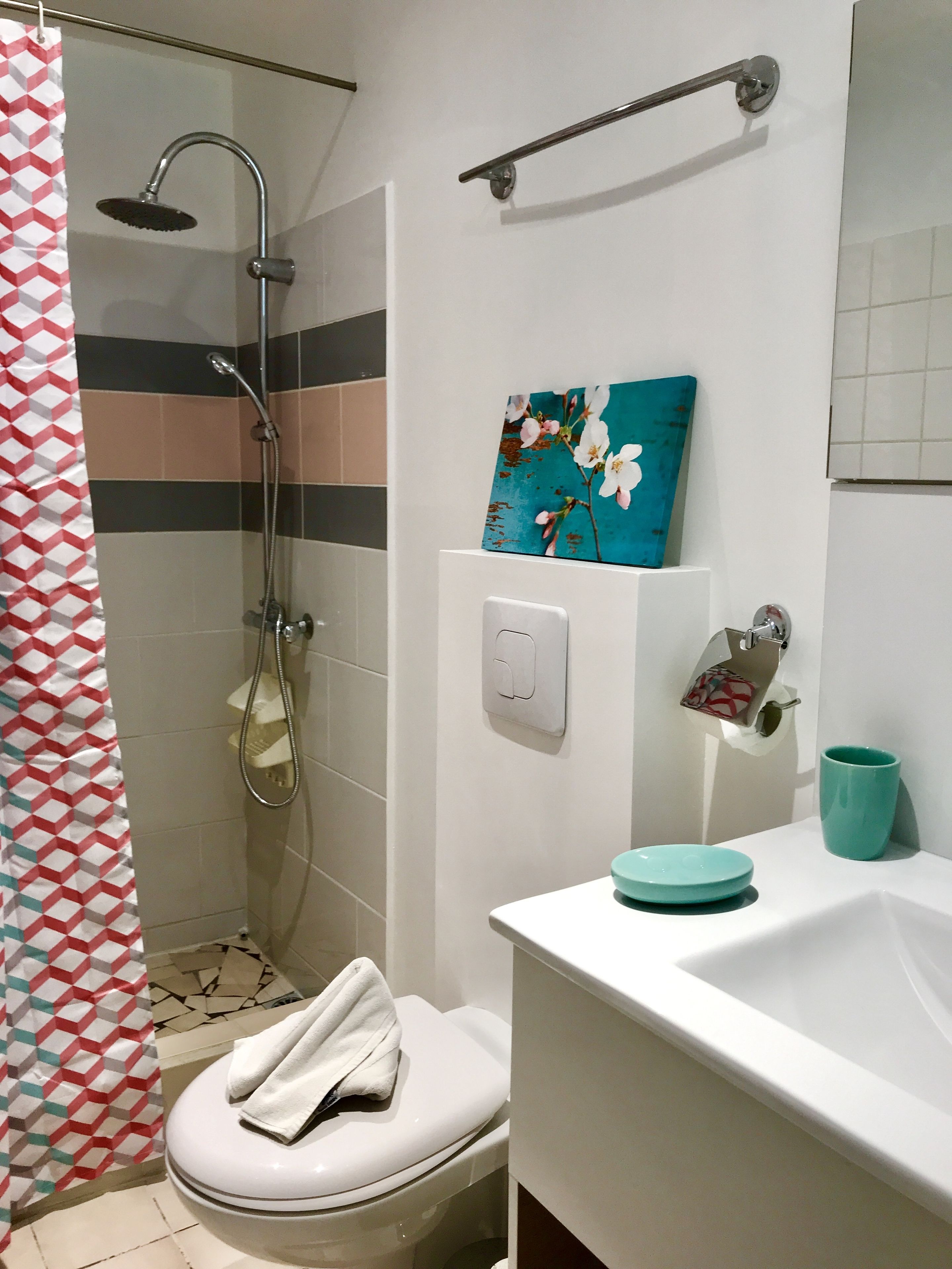 A bathroom with a shower, toilet, sink, and a towel hanging on the toilet.