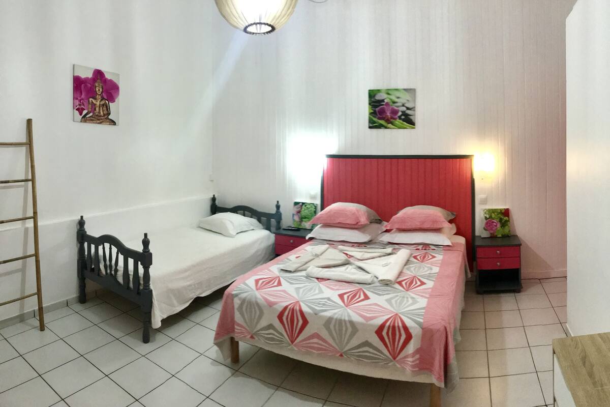 A bedroom with two beds, a wooden ladder, a nightstand, and a mirror.
