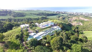 An aerial view of a resort with multiple buildings, a swimming pool, and lush greenery surrounding the property. - PARADIS TROPICAL appart'hotel (Baillif)