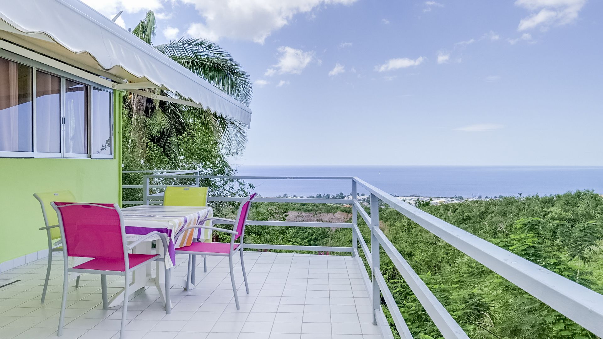 A terrace with a table and chairs, overlooking a coastal view.