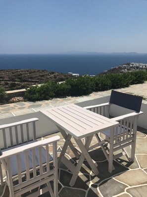 A patio with a table and chairs overlooking a coastal landscape.