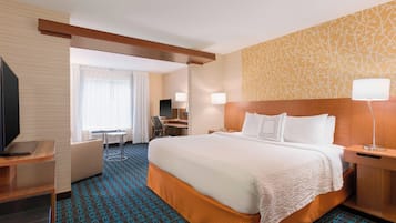 A hotel room with a large bed, a desk, and a TV.