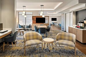 A modern hotel room with a large bed, a desk with a computer, a flat-screen TV, and a seating area with chairs and a small table. - TownePlace Suites Minneapolis near Mall of America (Bloomington)