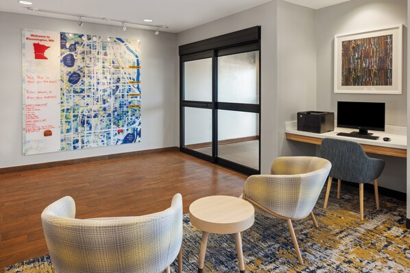 Un espacio de oficina moderno con un mapa grande en la pared, un escritorio con computadora, dos sillas y un ventanal amplio.
