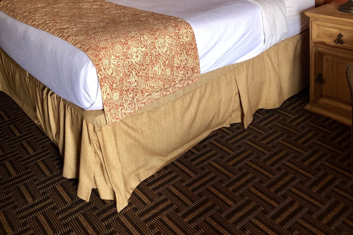 Ein Hotelzimmer mit einem großen Bett, einem Holzkopfende und einem Nachttisch mit Lampe.