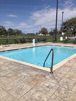 Piscina rectangular con una escalera metálica en un lado, rodeada por una solana con baldosas.