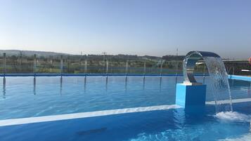 A clear blue swimming pool with a modern water feature.