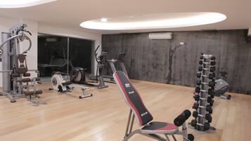Un gimnasio con diversos equipos de ejercicio, como bancos, mancuernas y máquinas de cardio.
