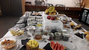 A buffet table with various food items including fruits, pastries, and condiments.