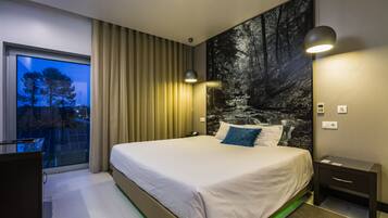 Une chambre d’hôtel moderne, dotée d’un grand lit, d’un bureau et offrant une vue sur le paysage urbain grâce à une grande fenêtre.