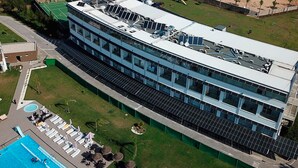 A modern building with a rooftop solar panel array, a swimming pool, and outdoor seating.