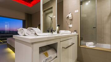 A modern bathroom with a vanity, towel storage, a hairdryer, and a glass-enclosed shower.