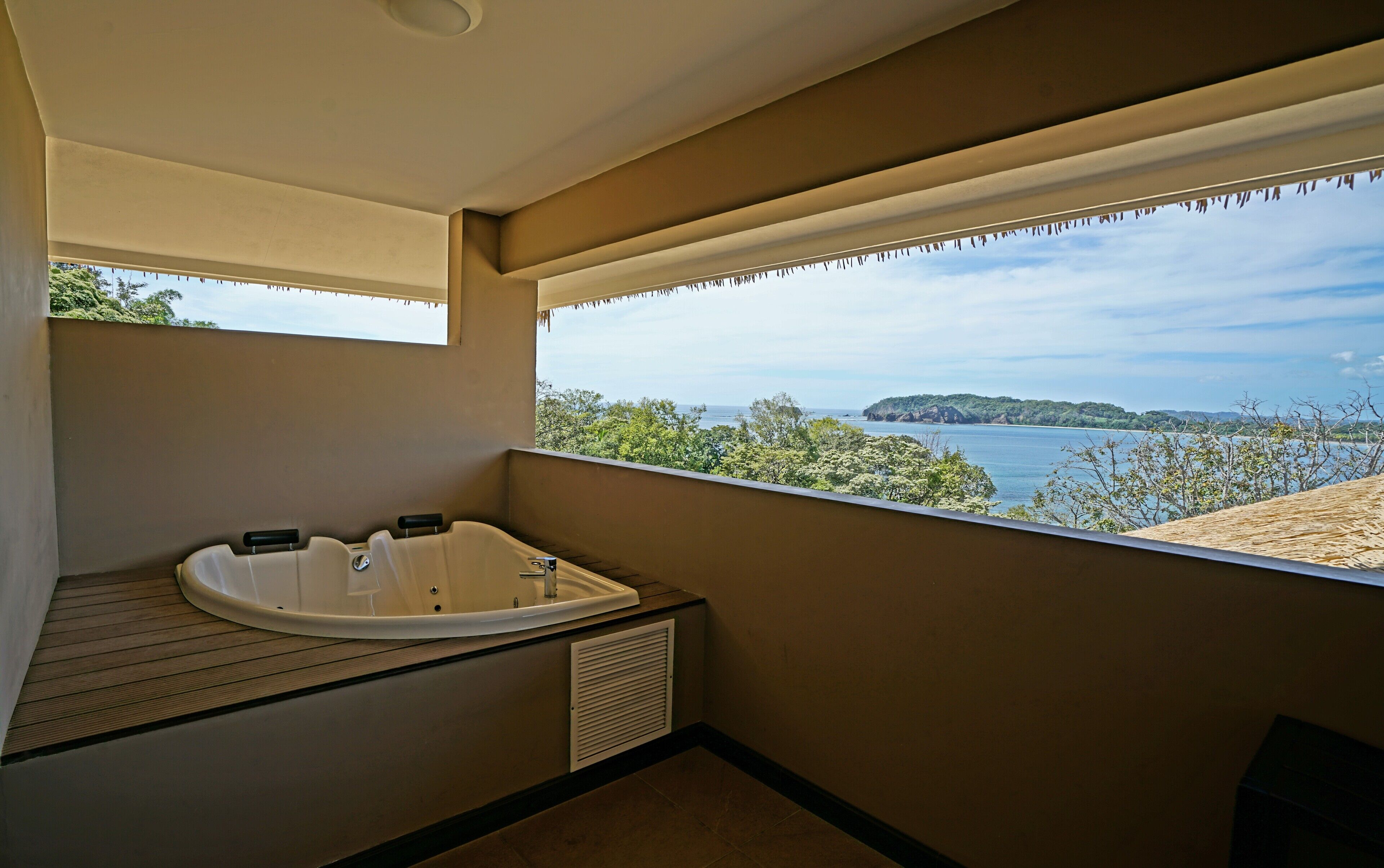 A balcony with a hot tub, a view of the sea, and a wooden deck.