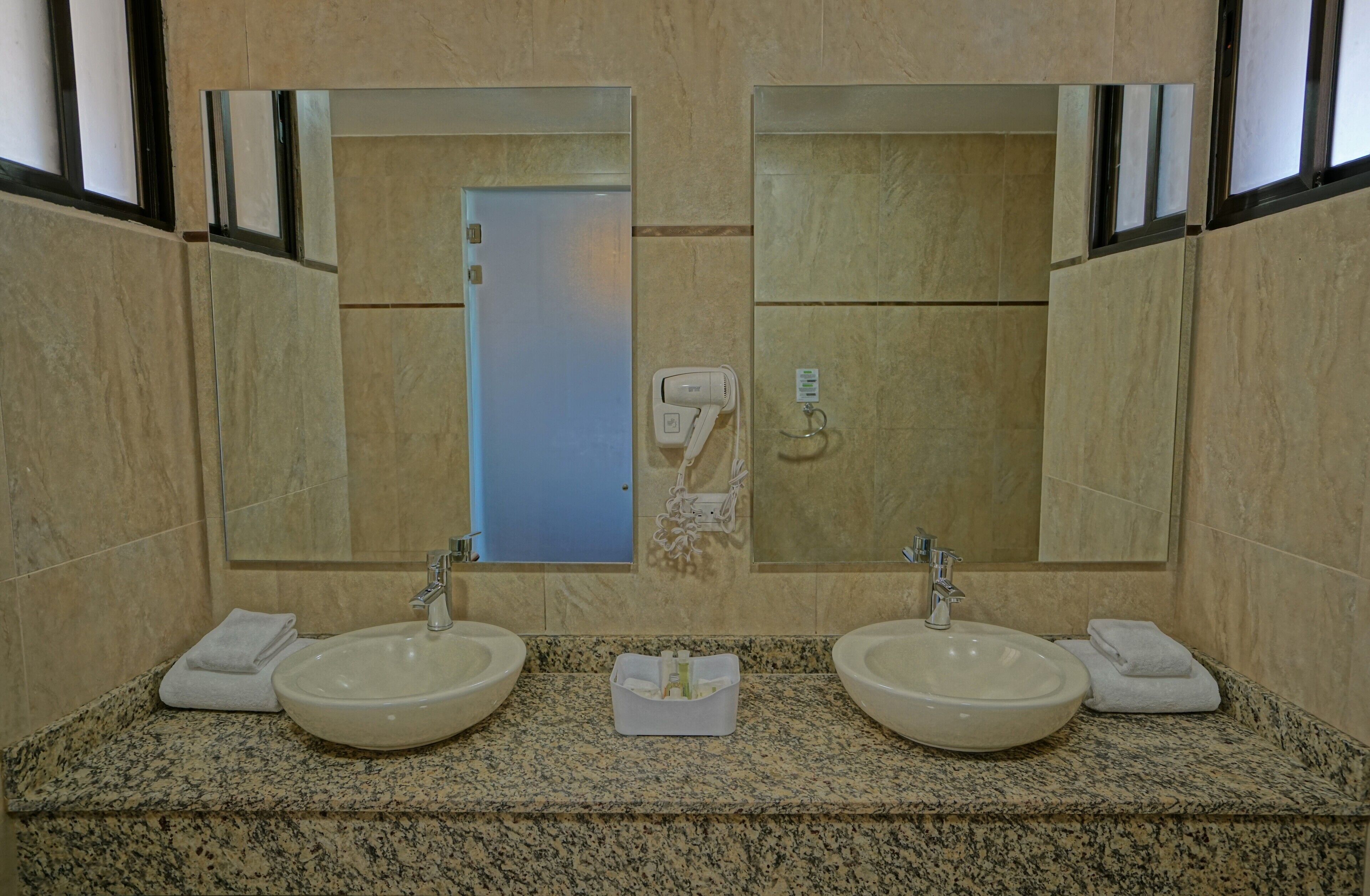 Un baño con dos lavamanos, un espejo y un perchero para toallas.