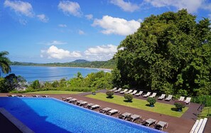 A pool with lounge chairs, a view of the sea, and lush greenery. - Nammbú Beachfront Bungalows (Puerto Carrillo)