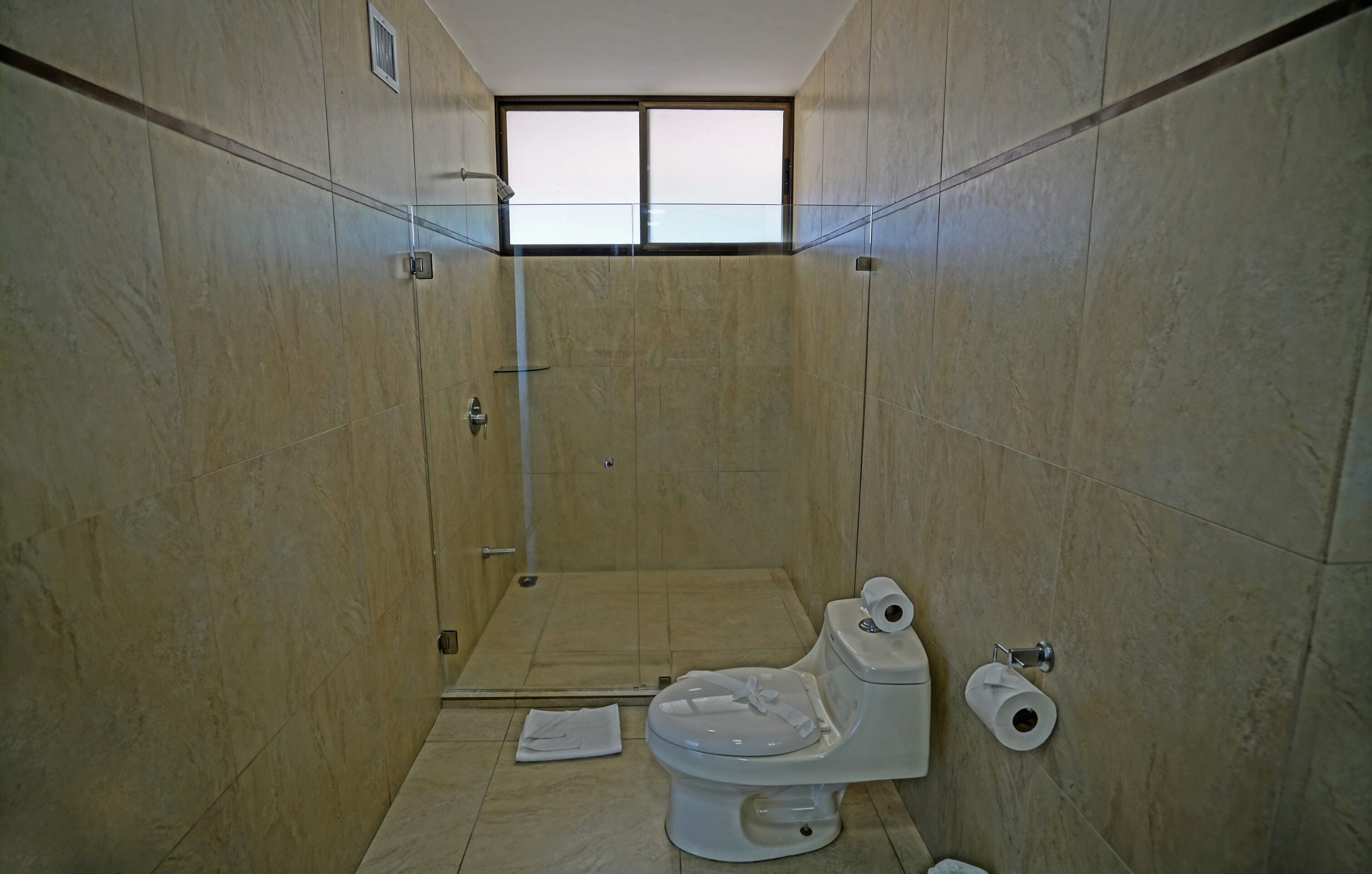 Un baño con inodoro, ducha y ventana.