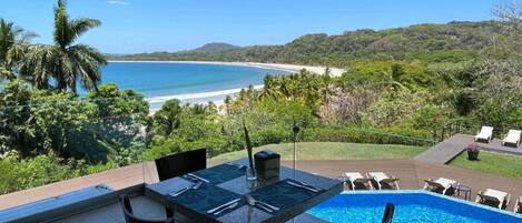 A poolside dining area with a view of the beach and ocean.