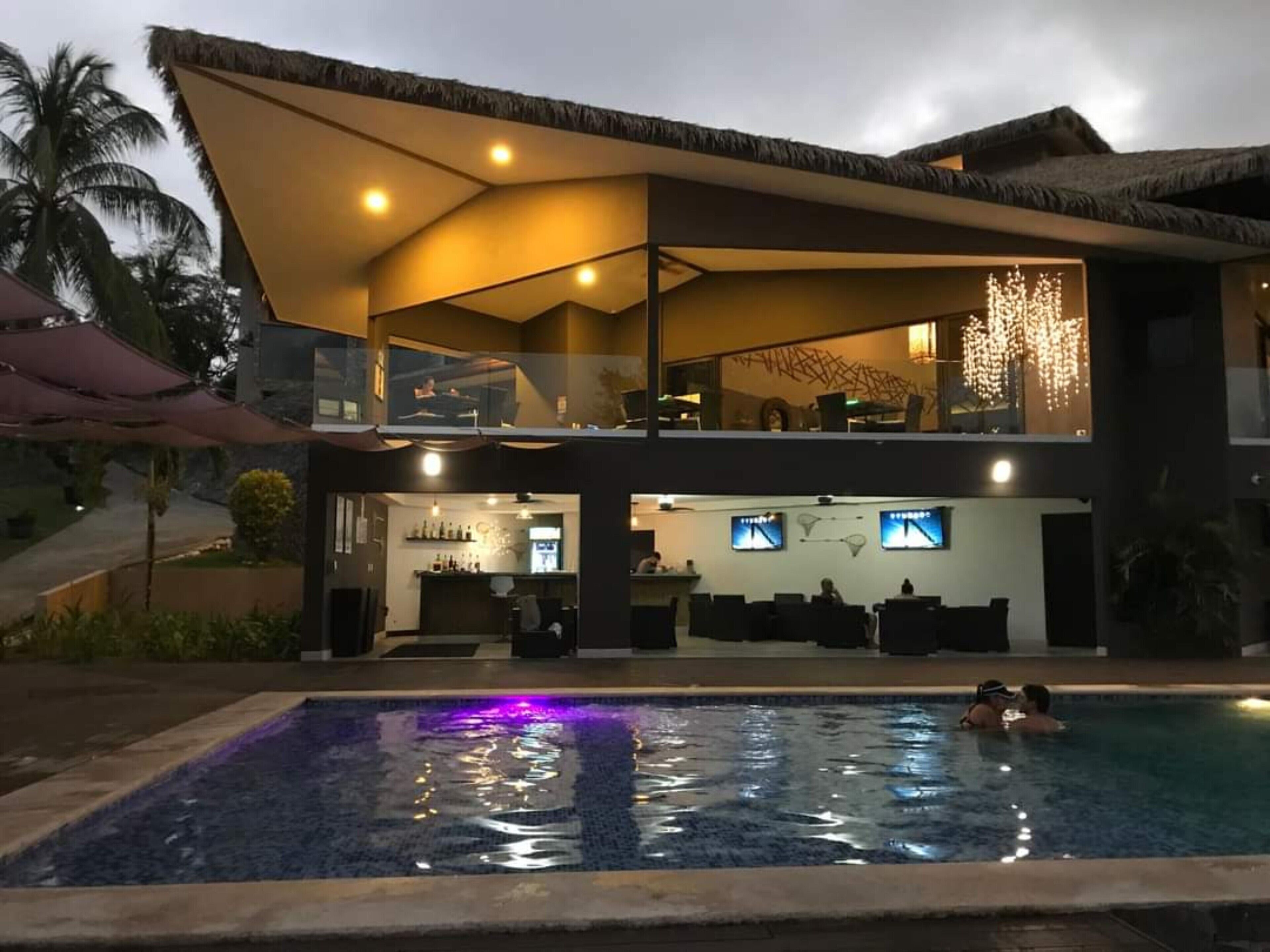 Una casa moderna de dos pisos con piscina, zona de bar y comedor.