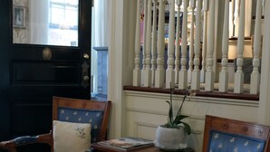 A room with two blue upholstered chairs with floral patterns, a small table with a plant, and a decorative white balustrade.