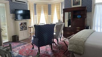 A room with a television, a wooden cabinet, a chair, a bed, and a patterned rug.