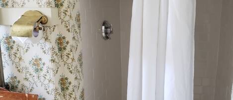 A bathroom with a shower curtain, a towel rack, and a wooden shelf.