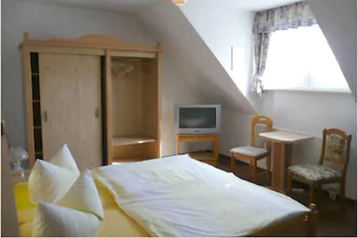 Ein Schlafzimmer mit Bett, Fernseher, Stuhl und Kleiderschrank.