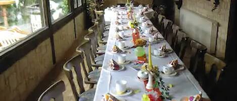 A long dining table set with plates, cups, and cutlery, surrounded by chairs.