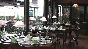 Un comedor interior con mesas dispuestas para comidas, sillas y lámparas colgantes.