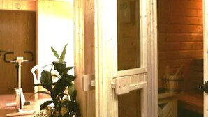 Interior de una cabaña de madera con una puerta de madera, una mesita y una planta en maceta.