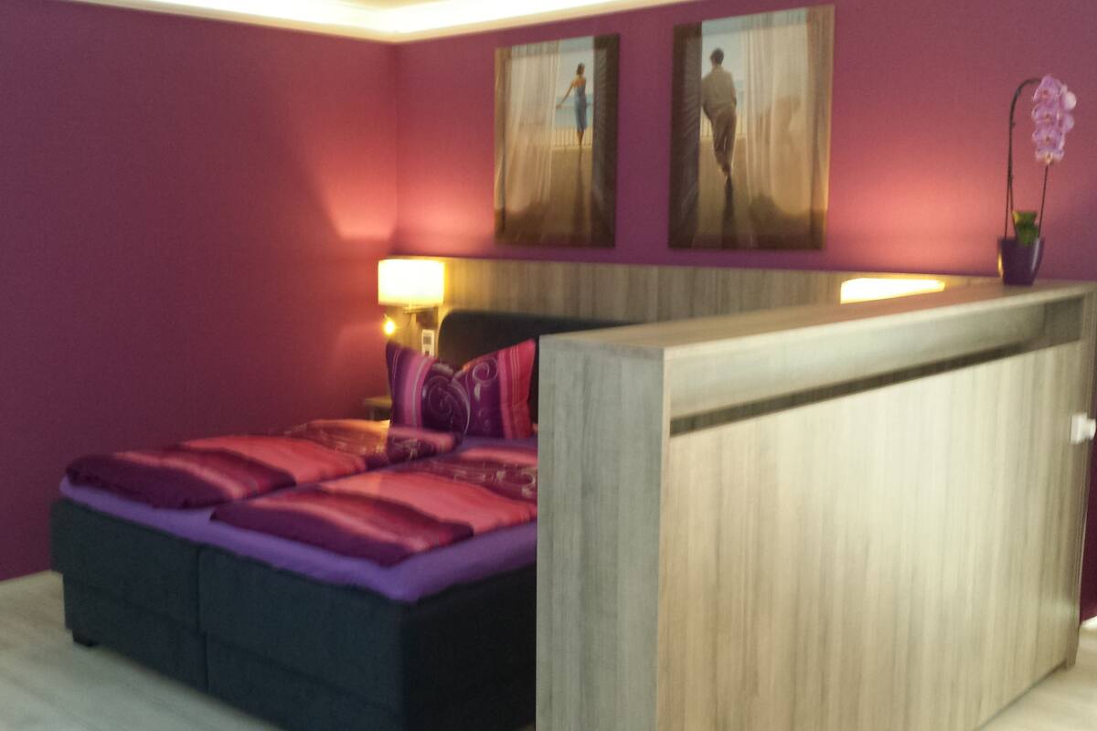 Ein Schlafzimmer mit einem Bett, einem Nachttisch und einer Wandlampe.